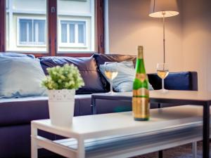 ein Wohnzimmer mit einem Sofa und einer Flasche Wein in der Unterkunft La Symphonie de l'Orangerie in Straßburg