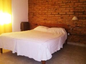 a bed in a room with a brick wall at Departamentos Las Grutas Enjoy in Las Grutas
