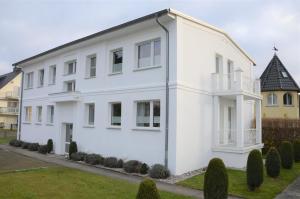 une maison blanche avec des buissons devant elle dans l'établissement Villa Herbstwind in Binz, à Binz