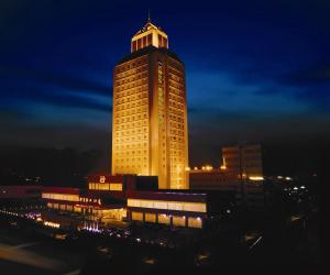 a tall building with a lit up tower at night at Grand Metropark Wanshi Hotel Taiyuan in Taiyuan