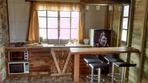 a kitchen with a table and stools in a room at Cabana Rústica Praia do Sonho in Palhoça