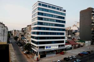 un grand bâtiment blanc avec un panneau bleu dans l'établissement Blu Sky Hotel, à Maputo