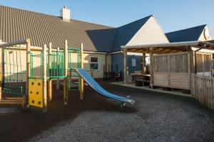 un parque infantil con un tobogán frente a una casa en The Raven’s Cliff Lodge by Marston's Inns en Motherwell