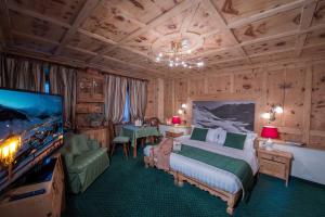 Hotel Alpina في ليفينو: غرفة نوم بسرير وتلفزيون بشاشة مسطحة