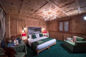 a bedroom with a large bed and a chandelier at Hotel Alpina in Livigno