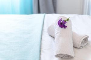 a couple of towels and a purple flower on a bed at Hacarmel Apartment in Tel Aviv