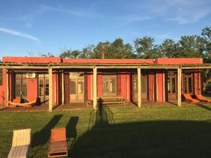 a red building with a red roof in the grass at La Negrita Casa de Campo in Azcuénaga