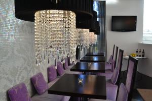 Hotel In - Lounge Room في كاتْساغو دي بيانيغا: صف من الطاولات والكراسي الأرجوانية في المطعم