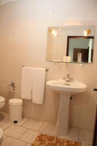 a bathroom with a sink and a toilet and a mirror at Restaurante e Residencial O Resineiro in Vidago