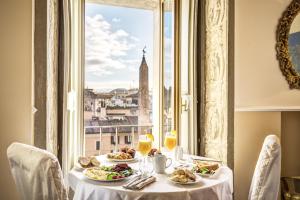 une table avec des assiettes de nourriture et une fenêtre dans l'établissement Eitch Borromini Palazzo Pamphilj, à Rome