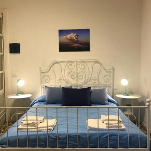 een slaapkamer met een wit bed met blauwe lakens bij B&B Perla in Catania