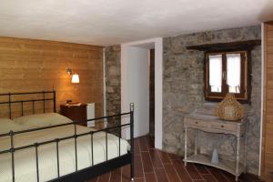 een slaapkamer met een bed en een stenen muur bij Agriturismo Grassi Lunghi in Pasturo
