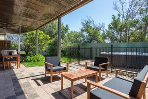 a patio with chairs and tables and a fence at Ocean Breeze Retreat - with spa and space in Saint Andrews Beach