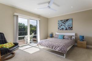 a bedroom with a bed and a chair and a window at Ocean Breeze Retreat - with spa and space in Saint Andrews Beach