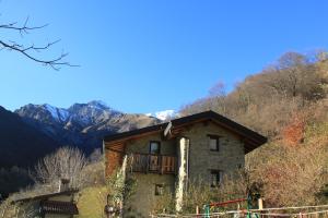 una casa en una colina con montañas en el fondo en Agriturismo Grassi Lunghi, en Pasturo