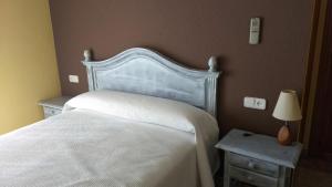 Cúllar de BazaにあるHostal Venta del Peralのベッドルーム1室(白いベッド1台、ナイトテーブル2台付)