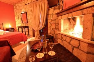 Synikia Mesi TrikalonにあるXENIOS ZEYS (ΞΕΝΙΟΣ ΖΕΥΣ)の石造りの暖炉、ベッド、テーブル(グラス付)が備わる客室です。