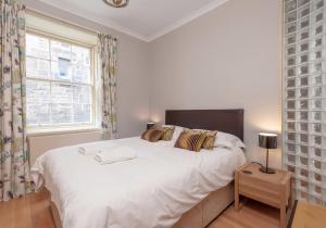 Un dormitorio con una gran cama blanca y una ventana en Parliament Sq (apt 3) Royal Mile en Edimburgo
