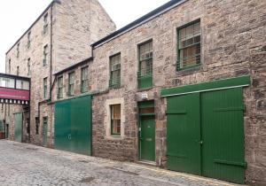 ein Backsteingebäude mit grünen Türen auf einer Straße in der Unterkunft Apartment Thistle Lane in Edinburgh