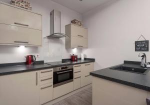 a kitchen with white cabinets and black counter tops at Castle Suite 2 Old Town in Edinburgh