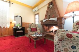 a living room with a fireplace and two chairs at Xenonas Epavli in Levidi