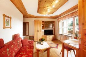 a living room with a red couch and a table at Gästehaus Apfelbacher in Spiegelau