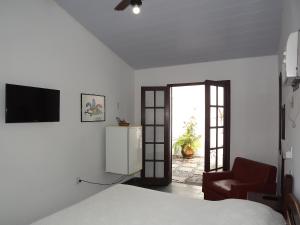 a bedroom with a bed and a television and a chair at Pousada Catavento in Saquarema