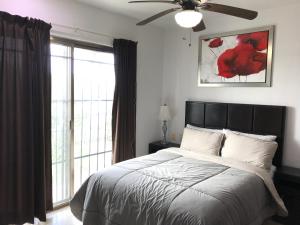 a bedroom with a bed with a ceiling fan and a window at Lilas del Mar Apartments in Playa del Carmen
