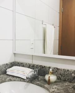 een wastafel met een spiegel en een handdoek bij Residencial Club em João Pessoa in João Pessoa