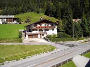 ein Haus auf einem Hügel neben einer Straße in der Unterkunft Pension Seeberger in Wald am Arlberg