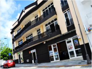 a black and yellow building with a red car parked in front at Apartamentos Jucar in Frontera