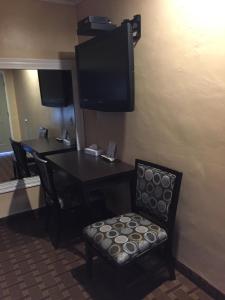 a room with a table and a chair and a television at Friendship Motor Inn in Los Angeles