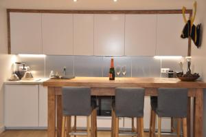 a kitchen with a wooden counter with chairs and a bottle of wine at Les Cîmes - Cosy apartment in Val-d'Isère