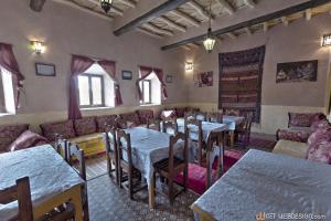 a restaurant with tables and couches in a room at Kasbah Ounila in Aït Ben Haddou