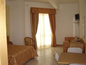 a hotel room with a bed and a couch and a window at Hotel Residence Charly in Lido di Fermo