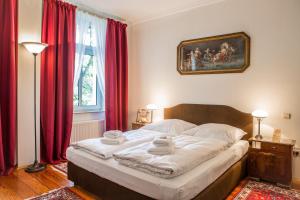 a bedroom with a large bed with red curtains at Jahrhunderthotel Leipzig in Leipzig