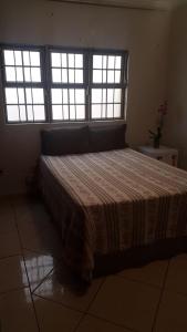a bedroom with a large bed with two windows at Quartos Uberlandia in Uberlândia