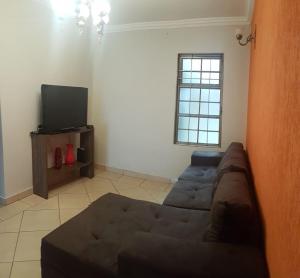 a living room with a couch and a tv at Quartos Uberlandia in Uberlândia