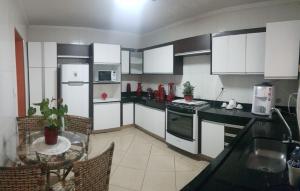 a kitchen with white appliances and a table with chairs at Quartos Uberlandia in Uberlândia