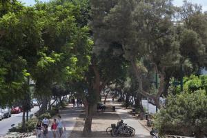 テルアビブにあるTLV Living Apartmentの木々に囲まれた歩道と人々が歩いている通り