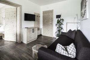 a living room with a black couch and a tv at Haus Spielbichl in San Lorenzo di Sebato