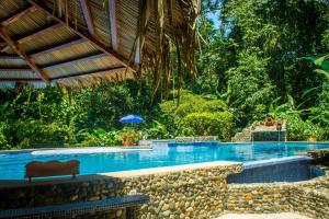 a swimming pool in a resort with an umbrella at The Goddess Garden Eco-Resort in Cahuita