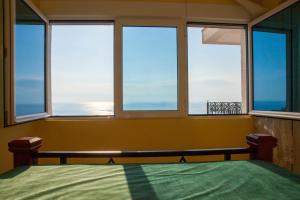 a bedroom with a bed and three windows with the ocean at Villa Edelweiss in Sveti Stefan