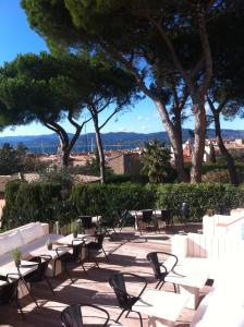 a patio with chairs and tables and trees at Hotel Ermitage in Saint-Tropez