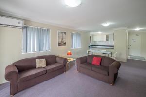una sala de estar con 2 sofás marrones y una sala de estar. en Parkside Apartments Parramatta, en Sídney