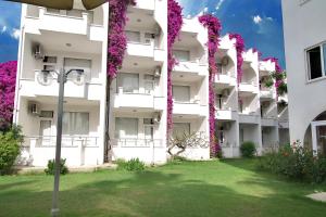 梅尔辛苏尔塔莎酒店的一栋白色公寓楼，上面开着紫色花朵