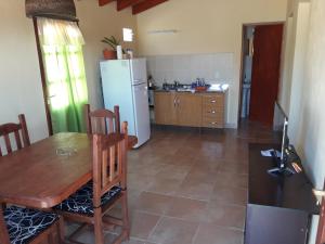 eine Küche mit einem Holztisch und einem Kühlschrank in der Unterkunft Cabaña Los Molles in Cachí