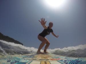 a woman riding a wave on a surfboard in the ocean at Hotel Perico Azul & Surf Camp in Jacó