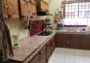 a kitchen with wooden cabinets and a counter top at Homestay Pagar Buruk Ipoh in Ipoh