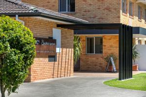 a brick building with a porch and a window at Beachpark Apartments Coffs Harbour in Coffs Harbour